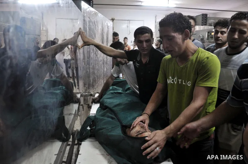 Palestinians look at the body of Palestinian man, whom medics said was killed in an Israeli in Shijaiyah neighborhood, to an emergency room at Shifa Hospital, in Gaza City, Wednesday, July 30, 2014. Photo by Mohammed Tal...