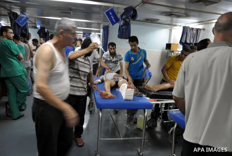 Palestinians wheel a wounded man, injured from an Israeli Strike in Shijaiyah neighborhood, to an emergency room at Shifa Hospital, in Gaza City, Wednesday, July 30, 2014. Photo by Mohammed Talatene