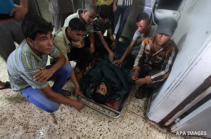 Palestinian relatives of Mahmud Rajab mourn outside the morgue of al-Shifa hospital in Gaza City on July 31, 2014. At least 10 people were killed in Israeli strikes on central and southern Gaza bringing the Palestinian d...