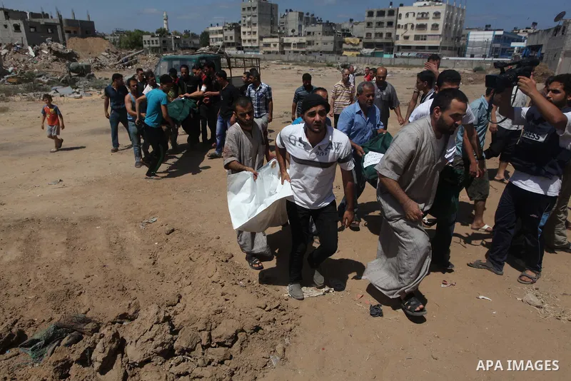 Palestinian men bury next to the bodies of Palestinians from the al-Silk family, whom medics said were killed by Israeli shelling near a market in Shejaia at a cemetery in Gaza City July 31, 2014. Israel did not comment...