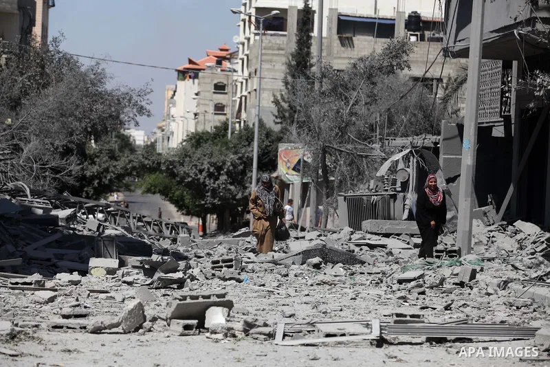 Palestinians walk past a building of Aqsa TV. destroyed by an Israeli air strike in Gaza city on July 31, 2014. Israel did not comment immediately on an incident on Wednesday, in nearby Shejaia, in which Palestinian offi...