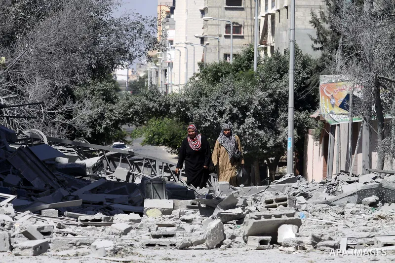 Palestinians walk past a building of Aqsa TV. destroyed by an Israeli air strike in Gaza city on July 31, 2014. Israel did not comment immediately on an incident on Wednesday, in nearby Shejaia, in which Palestinian offi...
