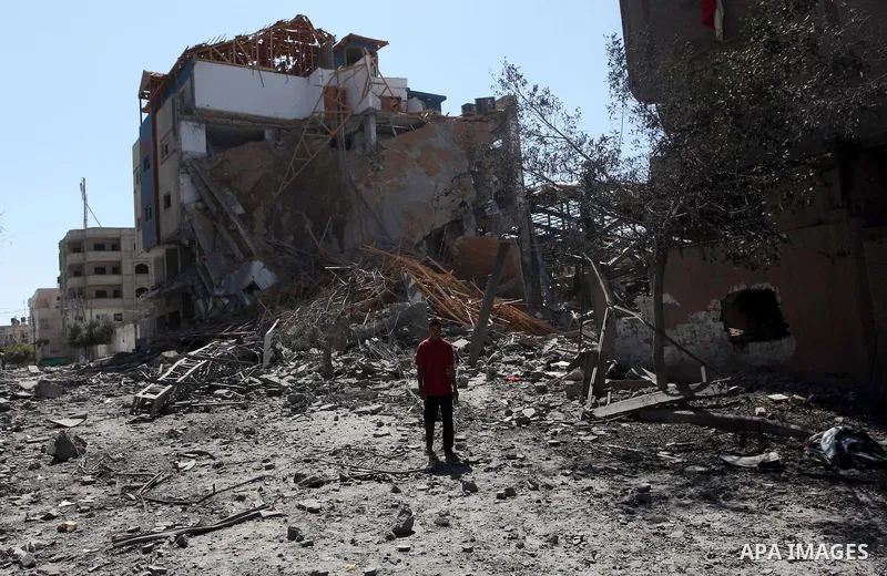 Palestinians walk past a building of Aqsa TV. destroyed by an Israeli air strike in Gaza city on July 31, 2014. Israel did not comment immediately on an incident on Wednesday, in nearby Shejaia, in which Palestinian offi...