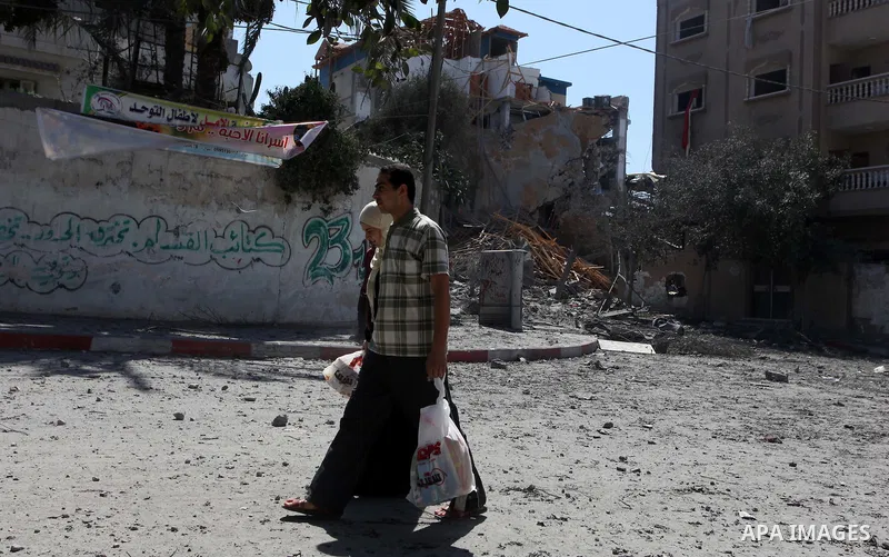 Palestinians walk past a building of Aqsa TV. destroyed by an Israeli air strike in Gaza city on July 31, 2014. Israel did not comment immediately on an incident on Wednesday, in nearby Shejaia, in which Palestinian offi...