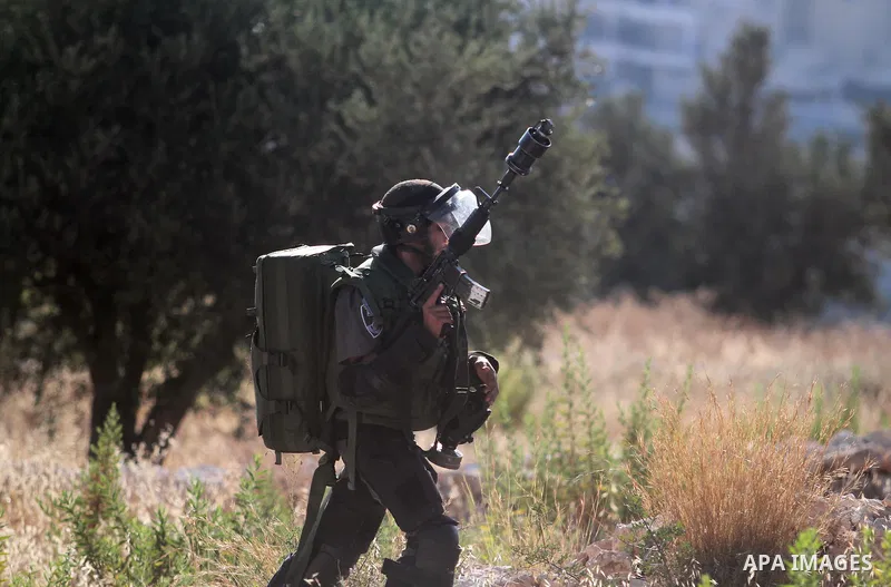 Palestinian protesters run for cover from tear-gas during clashes with Israeli soldiers following a demonstration in the West Bank village of Bilin, on July 31, 2014, in support of Palestinians from the Gaza Strip. Israe...
