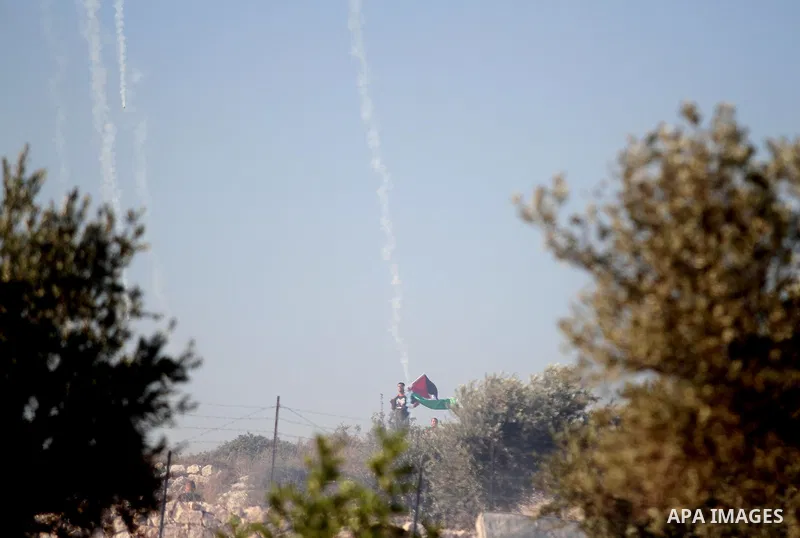 Palestinian protesters run for cover from tear-gas during clashes with Israeli soldiers following a demonstration in the West Bank village of Bilin, on July 31, 2014, in support of Palestinians from the Gaza Strip. Israe...