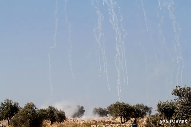 Palestinian protesters run for cover from tear-gas during clashes with Israeli soldiers following a demonstration in the West Bank village of Bilin, on July 31, 2014, in support of Palestinians from the Gaza Strip. Israe...