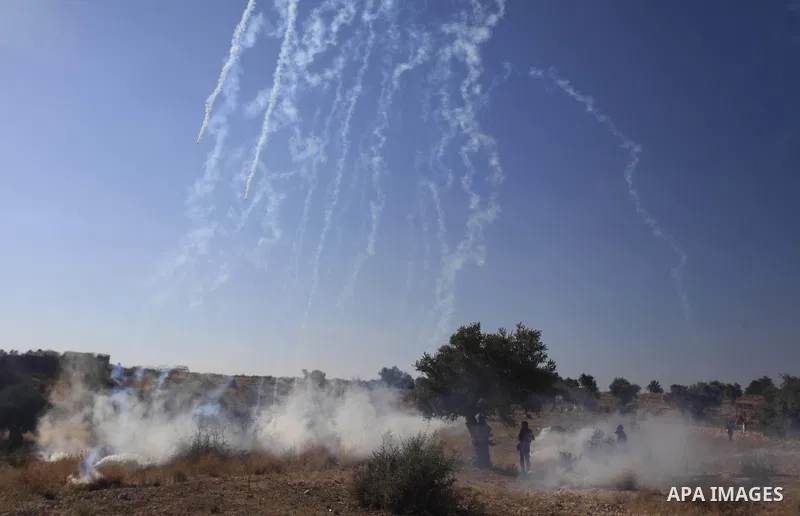 Palestinian protesters run for cover from tear-gas during clashes with Israeli soldiers following a demonstration in the West Bank village of Bilin, on July 31, 2014, in support of Palestinians from the Gaza Strip. Israe...