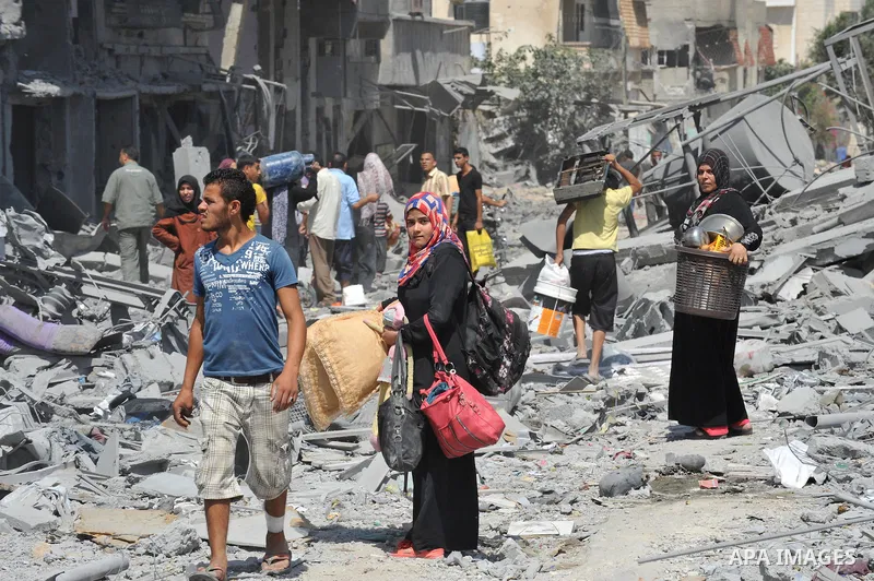 Palestinians carry their belongings from their destroyed houses in Beit Hanoun, Gaza Strip, August 1, 2014. A Gaza ceasefire was in jeopardy just hours after it began on Friday, with the Islamist group Hamas saying Israe...