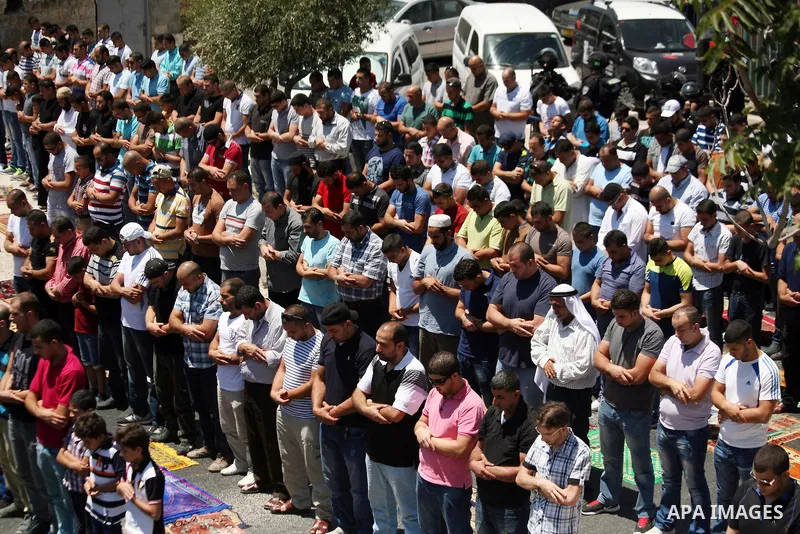 Palestinians pray as Israeli policemen guard during Friday prayers in the East Jerusalem neighbourhood of Wadi al-Joz August 1, 2014. Israeli police declared an age limit on Friday for Palestinians wanting to enter the O...