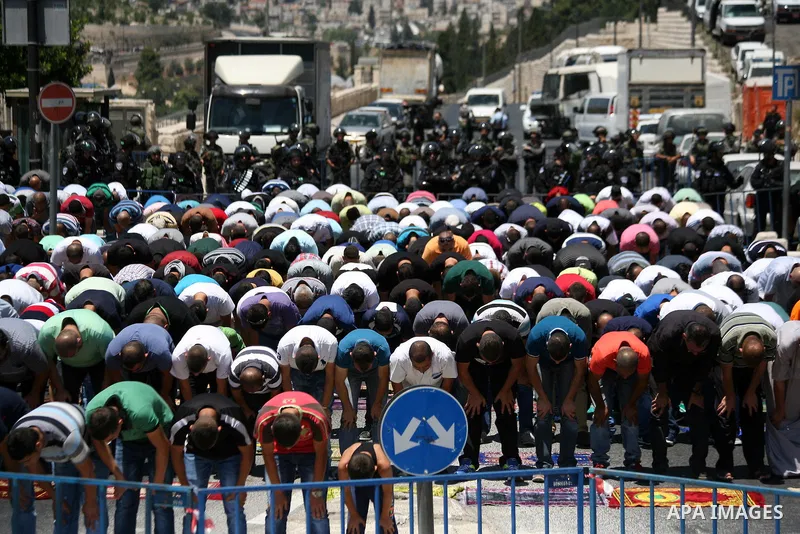 Palestinians pray as Israeli policemen guard during Friday prayers in the East Jerusalem neighbourhood of Wadi al-Joz August 1, 2014. Israeli police declared an age limit on Friday for Palestinians wanting to enter the O...