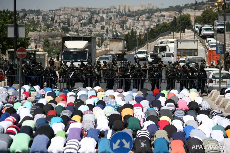 Palestinians pray as Israeli policemen guard during Friday prayers in the East Jerusalem neighbourhood of Wadi al-Joz August 1, 2014. Israeli police declared an age limit on Friday for Palestinians wanting to enter the O...