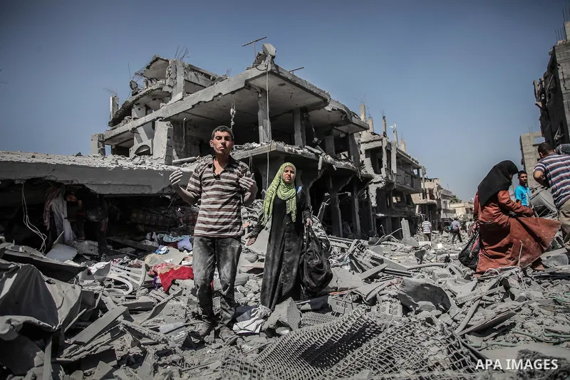 Palestinians carry their belongings after salvaging them from their destroyed house in the heavily bombed town of Beit Hanoun, Gaza Strip, close to the Israeli border, Friday, Aug. 1, 2014. A three-day Gaza cease-fire th...