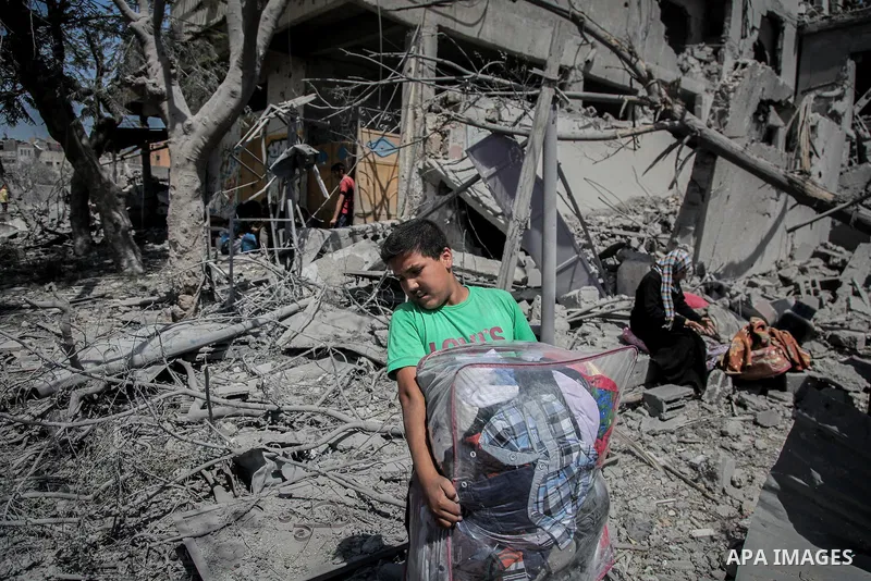 Palestinians carry their belongings after salvaging them from their destroyed house in the heavily bombed town of Beit Hanoun, Gaza Strip, close to the Israeli border, Friday, Aug. 1, 2014. A three-day Gaza cease-fire th...