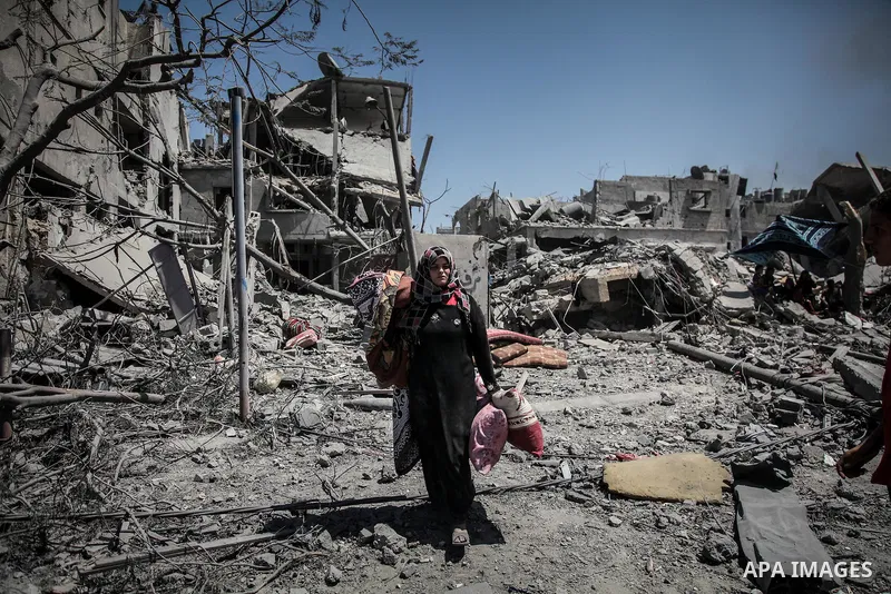Palestinians carry their belongings after salvaging them from their destroyed house in the heavily bombed town of Beit Hanoun, Gaza Strip, close to the Israeli border, Friday, Aug. 1, 2014. A three-day Gaza cease-fire th...