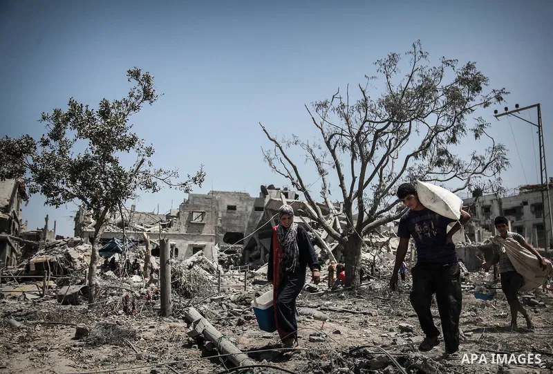 Palestinians carry their belongings after salvaging them from their destroyed house in the heavily bombed town of Beit Hanoun, Gaza Strip, close to the Israeli border, Friday, Aug. 1, 2014. A three-day Gaza cease-fire th...