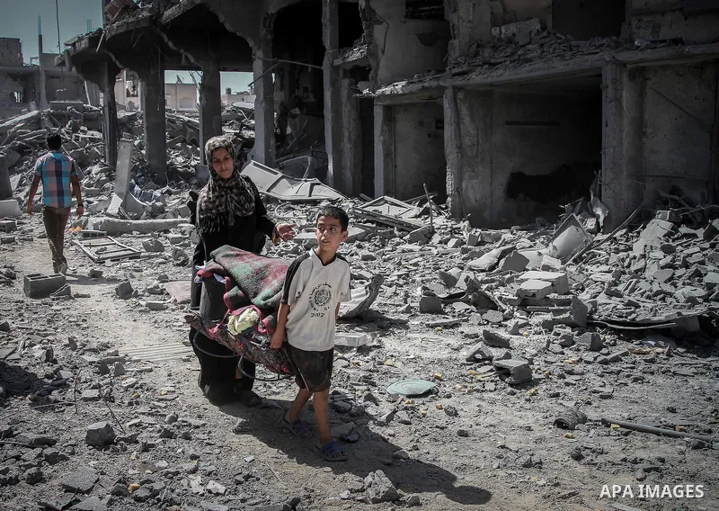 Palestinians carry their belongings after salvaging them from their destroyed house in the heavily bombed town of Beit Hanoun, Gaza Strip, close to the Israeli border, Friday, Aug. 1, 2014. A three-day Gaza cease-fire th...