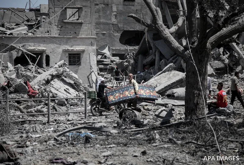 Palestinians carry their belongings after salvaging them from their destroyed house in the heavily bombed town of Beit Hanoun, Gaza Strip, close to the Israeli border, Friday, Aug. 1, 2014. A three-day Gaza cease-fire th...