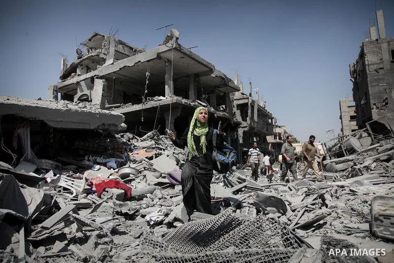 Palestinians carry their belongings after salvaging them from their destroyed house in the heavily bombed town of Beit Hanoun, Gaza Strip, close to the Israeli border, Friday, Aug. 1, 2014. A three-day Gaza cease-fire th...