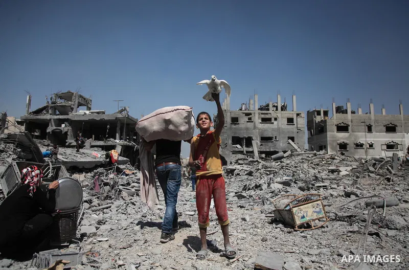 Palestinians carry their belongings after salvaging them from their destroyed house in the heavily bombed town of Beit Hanoun, Gaza Strip, close to the Israeli border, Friday, Aug. 1, 2014. A three-day Gaza cease-fire th...