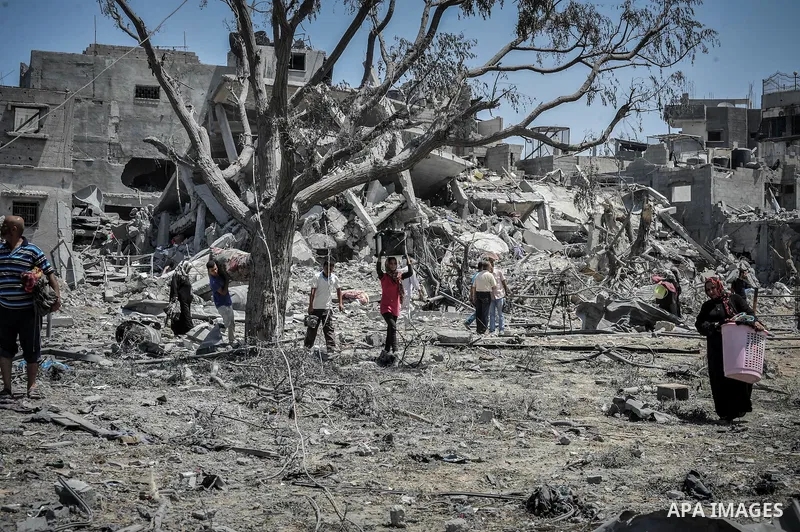 Palestinians carry their belongings after salvaging them from their destroyed house in the heavily bombed town of Beit Hanoun, Gaza Strip, close to the Israeli border, Friday, Aug. 1, 2014. A three-day Gaza cease-fire th...