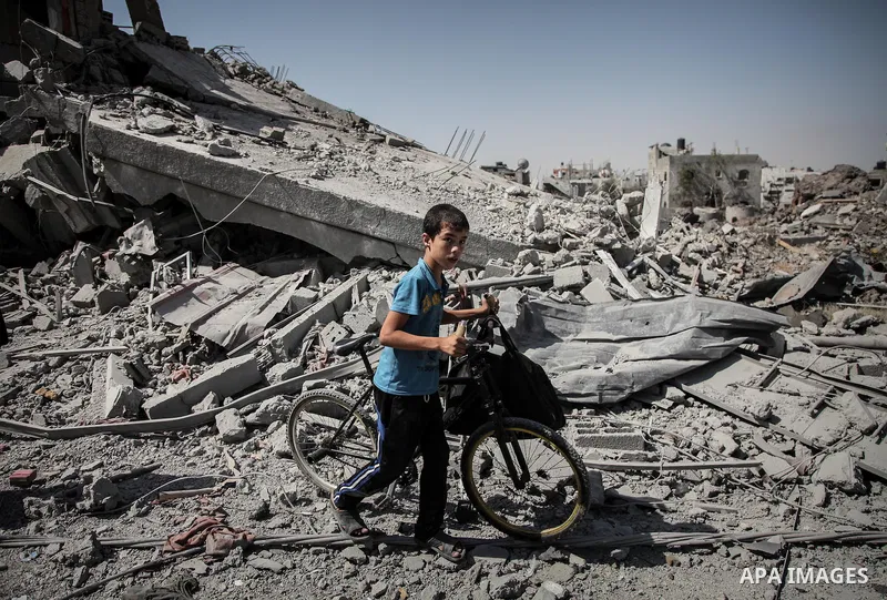 Palestinians carry their belongings after salvaging them from their destroyed house in the heavily bombed town of Beit Hanoun, Gaza Strip, close to the Israeli border, Friday, Aug. 1, 2014. A three-day Gaza cease-fire th...