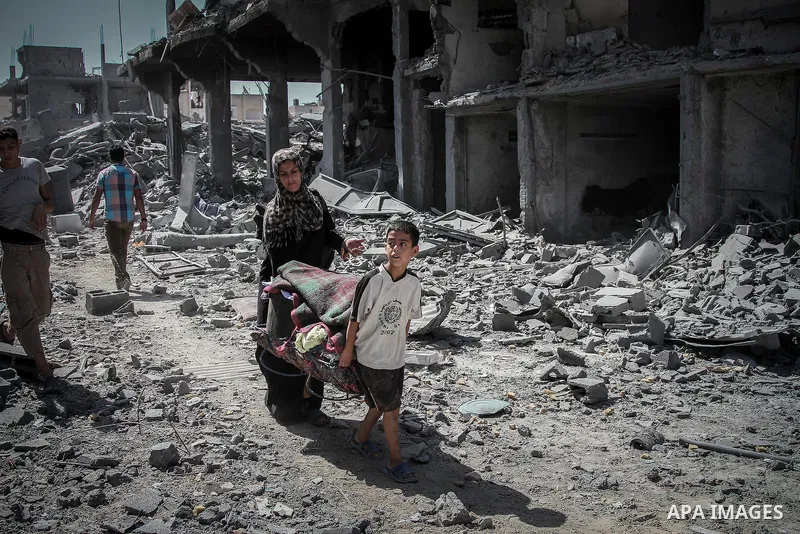 Palestinians carry their belongings after salvaging them from their destroyed house in the heavily bombed town of Beit Hanoun, Gaza Strip, close to the Israeli border, Friday, Aug. 1, 2014. A three-day Gaza cease-fire th...
