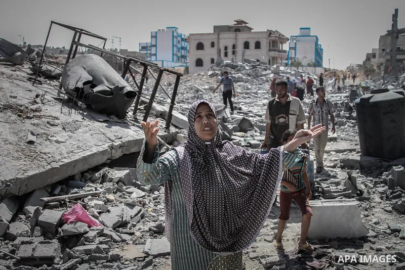 Palestinians carry their belongings after salvaging them from their destroyed house in the heavily bombed town of Beit Hanoun, Gaza Strip, close to the Israeli border, Friday, Aug. 1, 2014. A three-day Gaza cease-fire th...