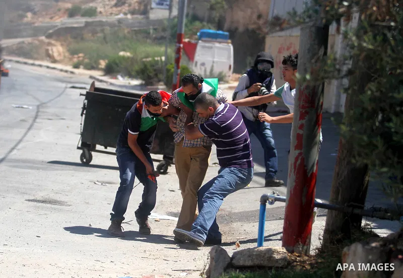 A Palestinian protester kicks a burning tyre during clashes with Israeli troops at a protest against the Israeli offensive in Gaza, outside Israel's Ofer military prison near the West Bank city of Ramallah August 1,2014....