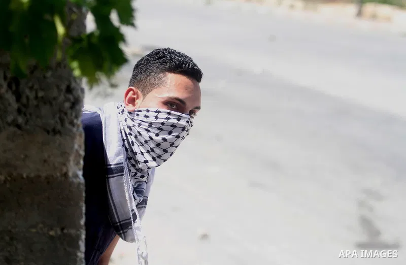 A Palestinian protester kicks a burning tyre during clashes with Israeli troops at a protest against the Israeli offensive in Gaza, outside Israel's Ofer military prison near the West Bank city of Ramallah August 1,2014....