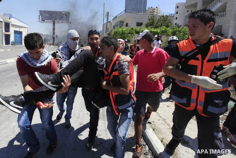 A Palestinian protester kicks a burning tyre during clashes with Israeli troops at a protest against the Israeli offensive in Gaza, outside Israel's Ofer military prison near the West Bank city of Ramallah August 1,2014....