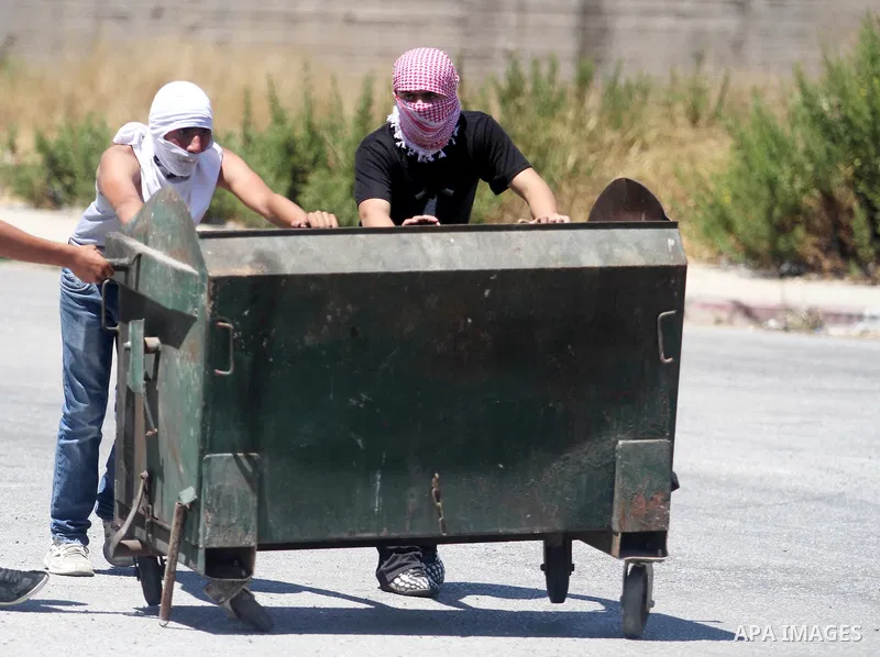 A Palestinian protester kicks a burning tyre during clashes with Israeli troops at a protest against the Israeli offensive in Gaza, outside Israel's Ofer military prison near the West Bank city of Ramallah August 1,2014....