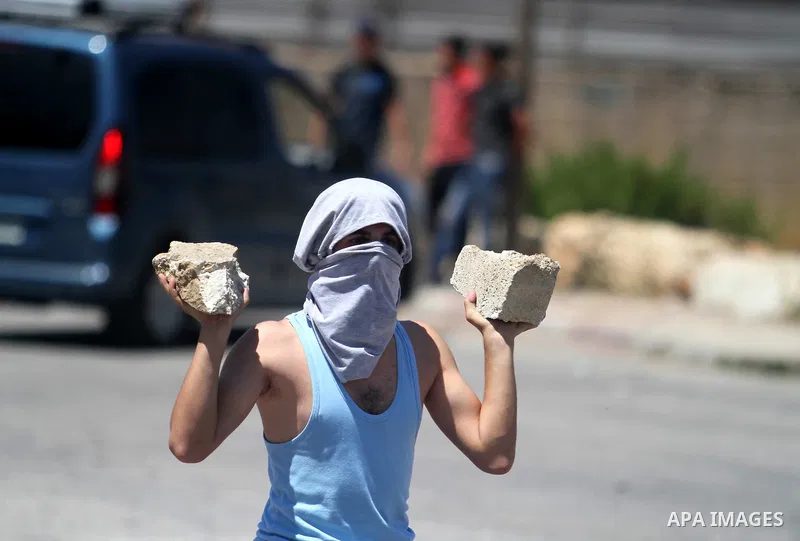 A Palestinian protester kicks a burning tyre during clashes with Israeli troops at a protest against the Israeli offensive in Gaza, outside Israel's Ofer military prison near the West Bank city of Ramallah August 1,2014....
