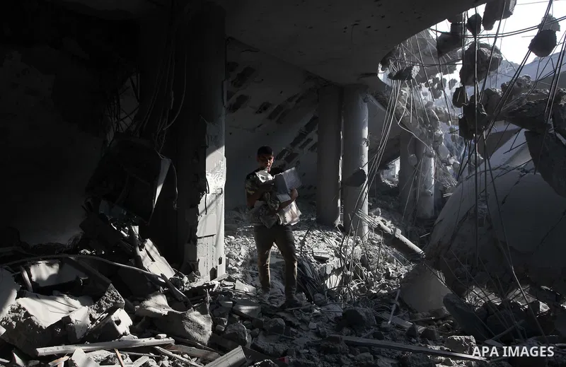 A Palestinian man carries pages of destroyed copies of the Koran, Islam's holy book, on August 2, 2014 after a mosque was hit in an overnight Israeli strike on Gaza City. A fresh wave of violence killed dozens in Gaza af...