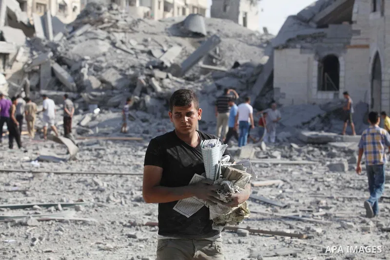 A Palestinian man carries pages of destroyed copies of the Koran, Islam's holy book, on August 2, 2014 after a mosque was hit in an overnight Israeli strike on Gaza City. A fresh wave of violence killed dozens in Gaza af...