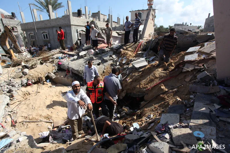 Rescue workers search for victims as Palestinians gather around the wreckage of a house, which witnesses said was destroyed in an Israeli air strike that killed at least five members from the al-Khattab family, in Deir a...