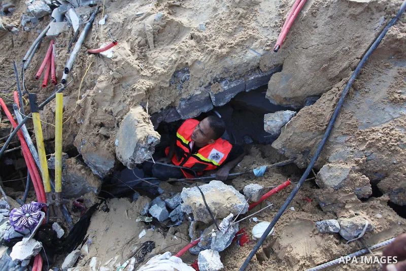 Rescue workers search for victims as Palestinians gather around the wreckage of a house, which witnesses said was destroyed in an Israeli air strike that killed at least five members from the al-Khattab family, in Deir a...