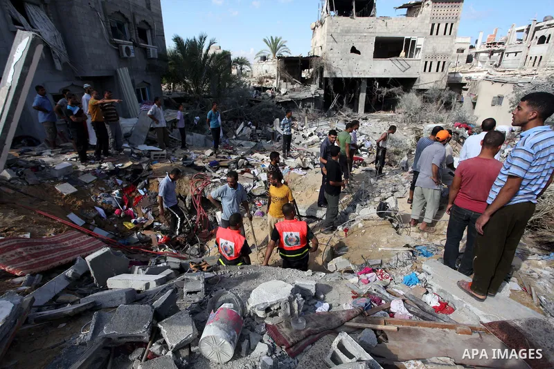 Rescue workers search for victims as Palestinians gather around the wreckage of a house, which witnesses said was destroyed in an Israeli air strike that killed at least five members from the al-Khattab family, in Deir a...