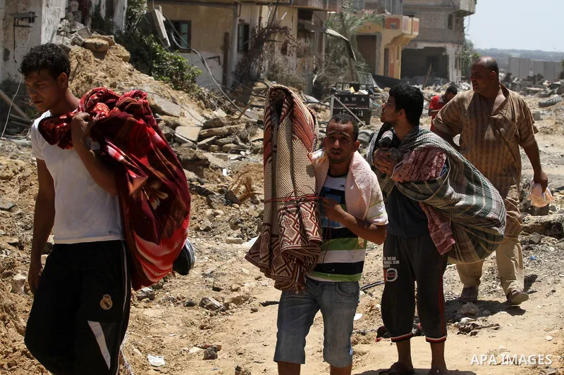 Palestinians carry belongings as they walk over the rubble of buildings destroyed by what police said were Israeli air strikes and shelling in Khuzaa, east of Khan Younis, in the southern Gaza Strip August 3, 2014. An Is...