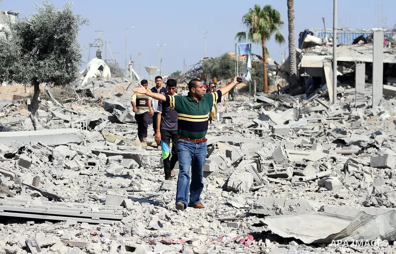 Palestinians walk past a houses damaged by what police said were Israeli air strikes and shelling in Khuzaa, east of Khan Younis, in the southern Gaza Strip August 3, 2014. An Israeli air strike killed at least 10 people...