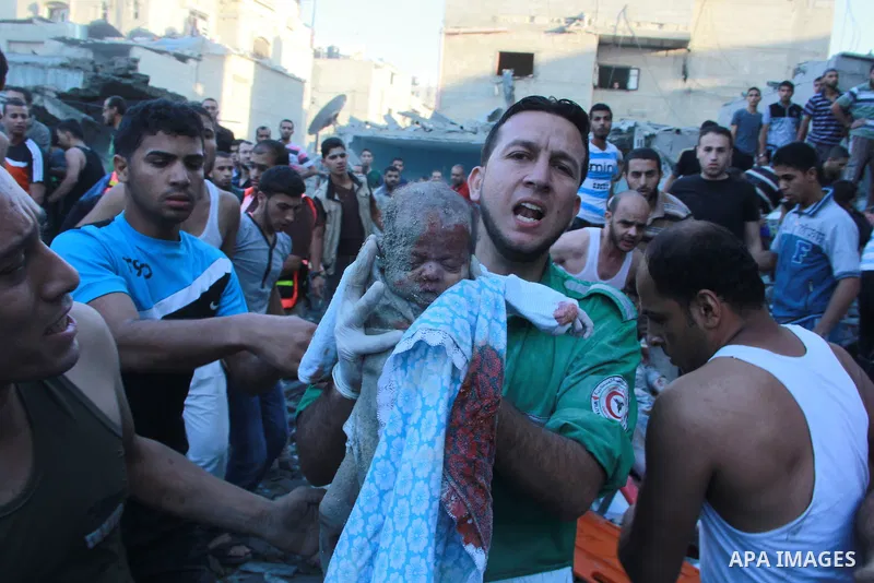 A paramedic carries the lifeless body of a baby after an Israeli air strike hit the Al Ghoul family building in Rafah, in the southern Gaza Strip, Sunday, Aug. 3, 2014. At least 40 people were inside the Al Ghoul family...