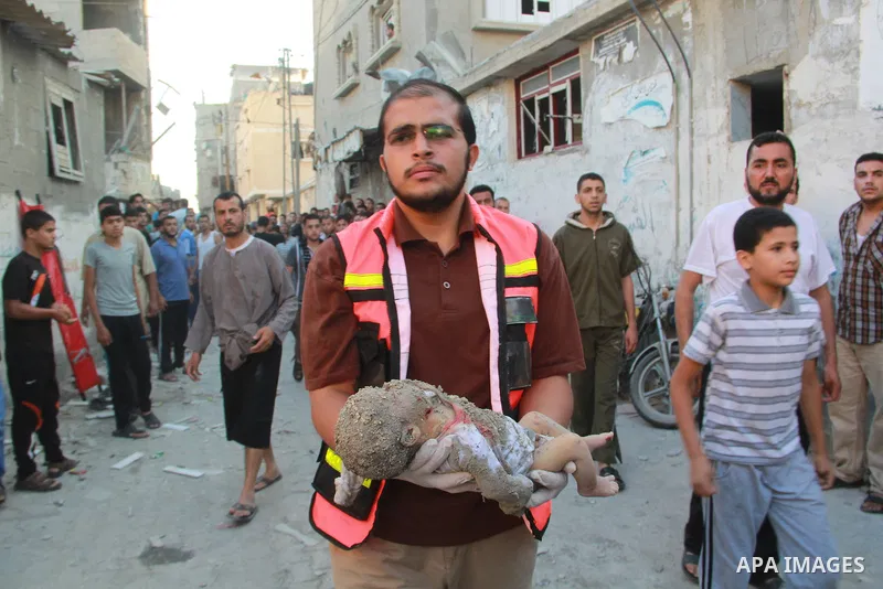 A paramedic carries the lifeless body of a baby after an Israeli air strike hit the Al Ghoul family building in Rafah, in the southern Gaza Strip, Sunday, Aug. 3, 2014. At least 40 people were inside the Al Ghoul family...