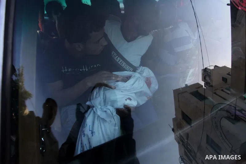 relative sits in a car as he carries the body of two-and-a-half-year-old Palestinian girl Raghad Massoud, whom medics said was killed in an Israeli air strike, before her burial in Rafah in the southern Gaza Strip August...