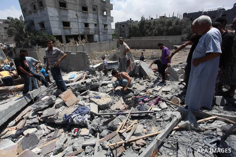 Palestinians gather as rescue workers search for victims under the rubble of a house which witnesses said was destroyed in an Israeli air strike, in Rafah in the southern Gaza Strip August 4, 2014. Palestinians accused I...