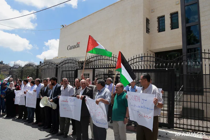 Palestinians hold banners during a protest against the policy of Canada in front of the Canadian Embassy, in the West Bank city of Ramallah, on August 4, 2014. Canada supported for the Israeli aggression on the Gaza Stri...