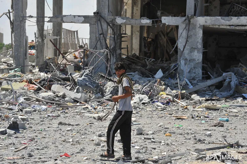 Palestinians walk in front of the rubble of buildings destroyed in Israeli strikes, in Beit Lahiya, northern Gaza Strip, Monday, Aug. 4, 2014.. Photo by Ezz al-Zanoun