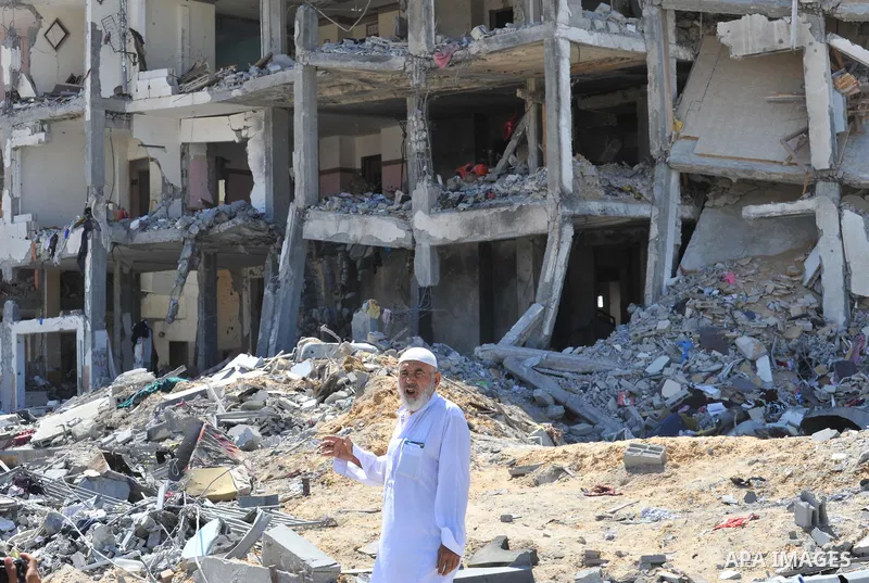 Palestinians walk in front of the rubble of buildings destroyed in Israeli strikes, in Beit Lahiya, northern Gaza Strip, Monday, Aug. 4, 2014.. Photo by Ezz al-Zanoun