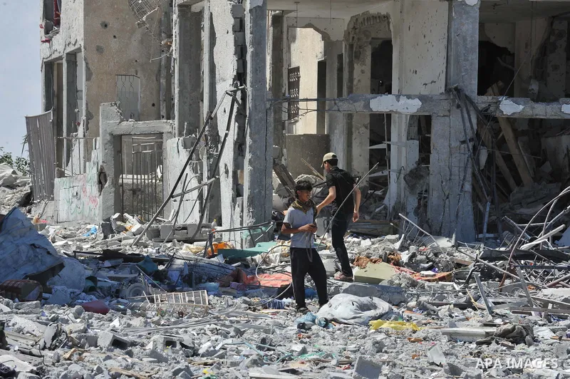 Palestinians walk in front of the rubble of buildings destroyed in Israeli strikes, in Beit Lahiya, northern Gaza Strip, Monday, Aug. 4, 2014.. Photo by Ezz al-Zanoun