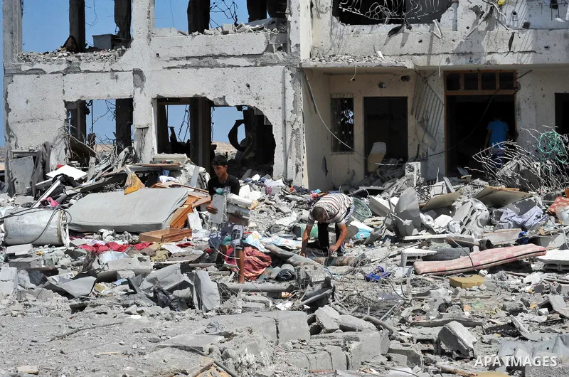 Palestinians walk in front of the rubble of buildings destroyed in Israeli strikes, in Beit Lahiya, northern Gaza Strip, Monday, Aug. 4, 2014.. Photo by Ezz al-Zanoun