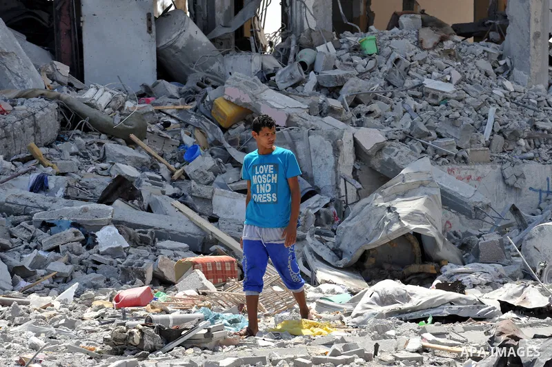 Palestinians walk in front of the rubble of buildings destroyed in Israeli strikes, in Beit Lahiya, northern Gaza Strip, Monday, Aug. 4, 2014.. Photo by Ezz al-Zanoun